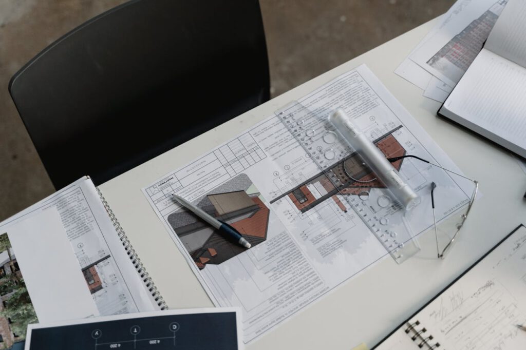 pexels-photo-6615239 Top view of architectural blueprints and drafting tools on a workspace desk.